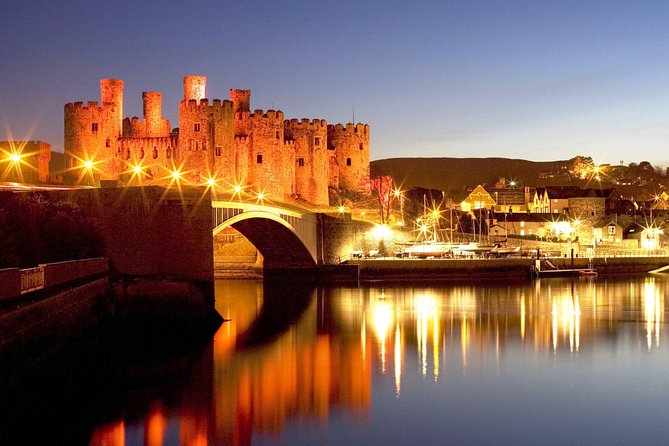 Castle walls floodlit above the water after dark